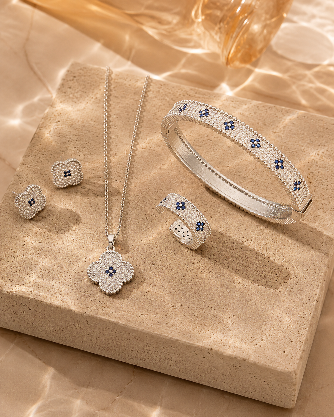 Silver jewelry set with blue stones on a beige stone surface